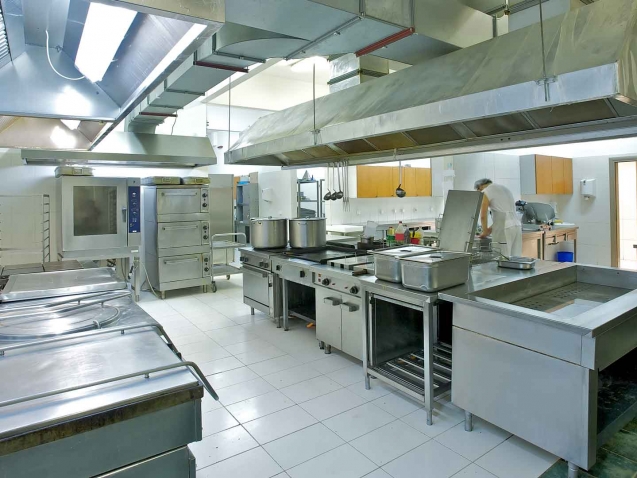 a view of a restaurant kitchen with a man working in the far corner